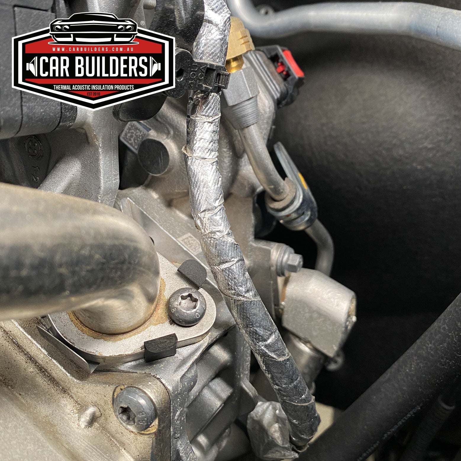 Wiring loom wrapped in heat reflective foil tape in an engine bay