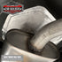 Heat reflective foil tape sealing a heat shield beside an exhaust muffler