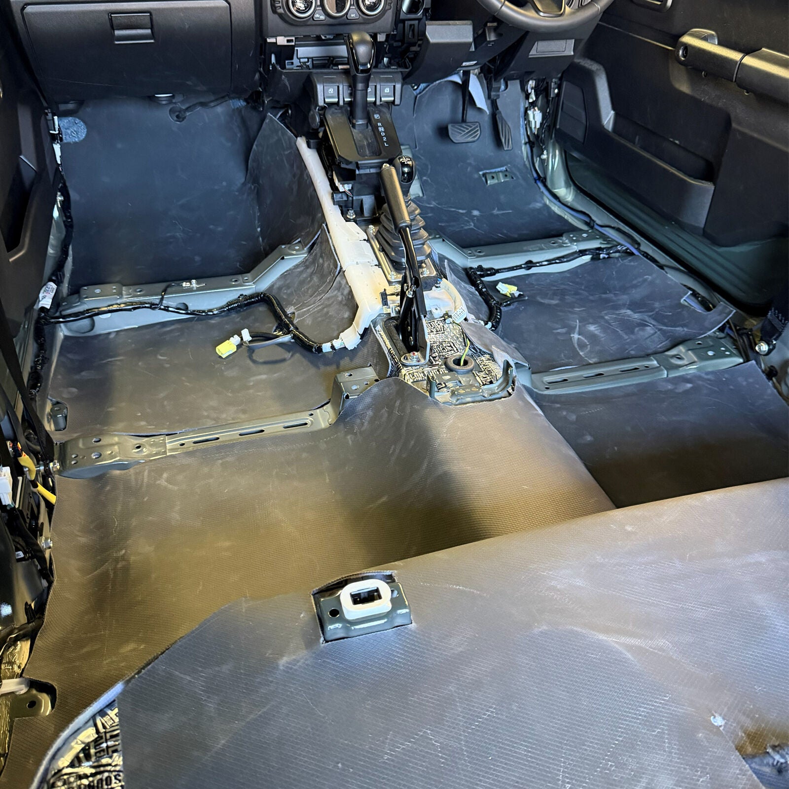 Installer laying mass loaded vinyl on a Jimny floor