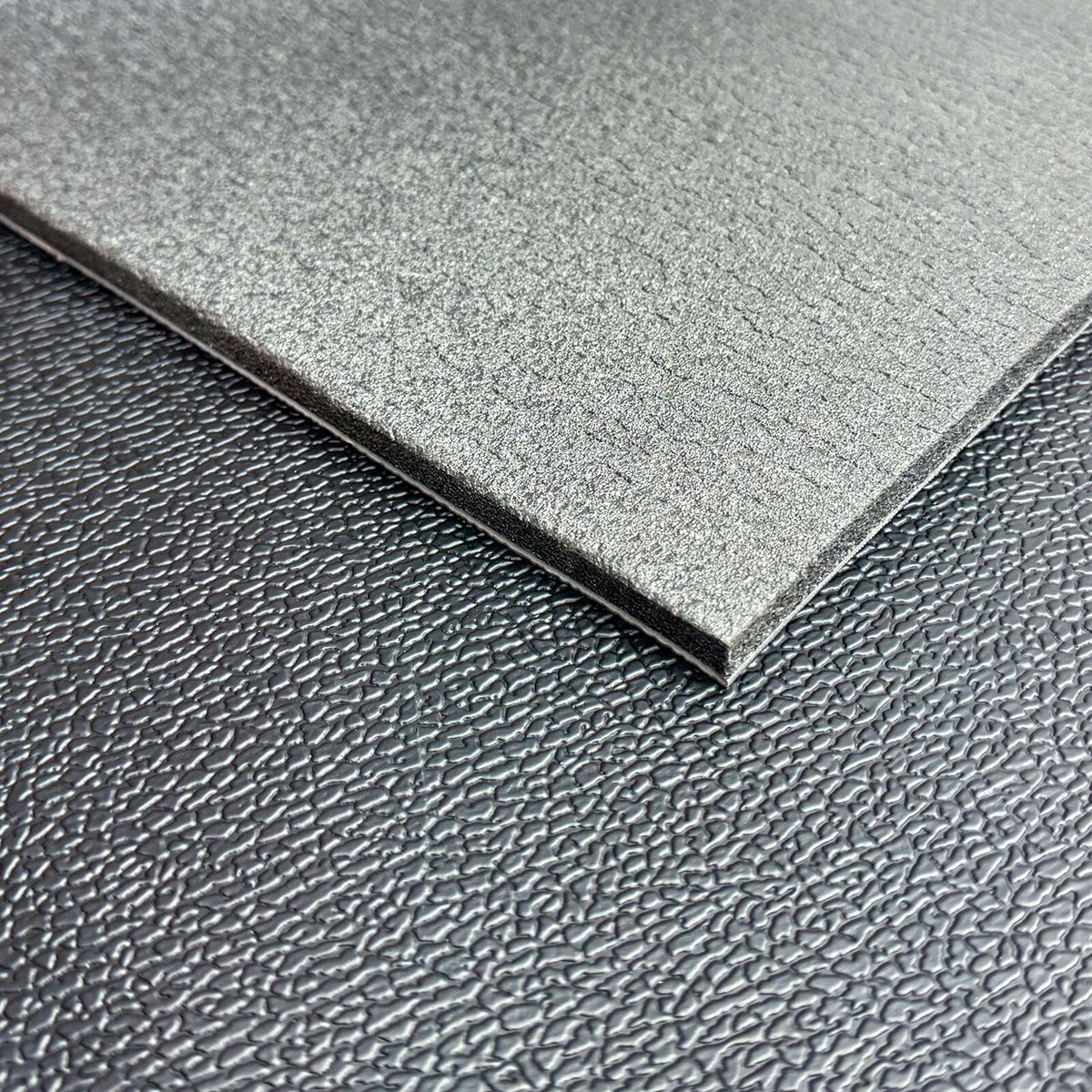 Cut edge of Sound Barrier Floor Mat showing backed and unbacked layers side by side