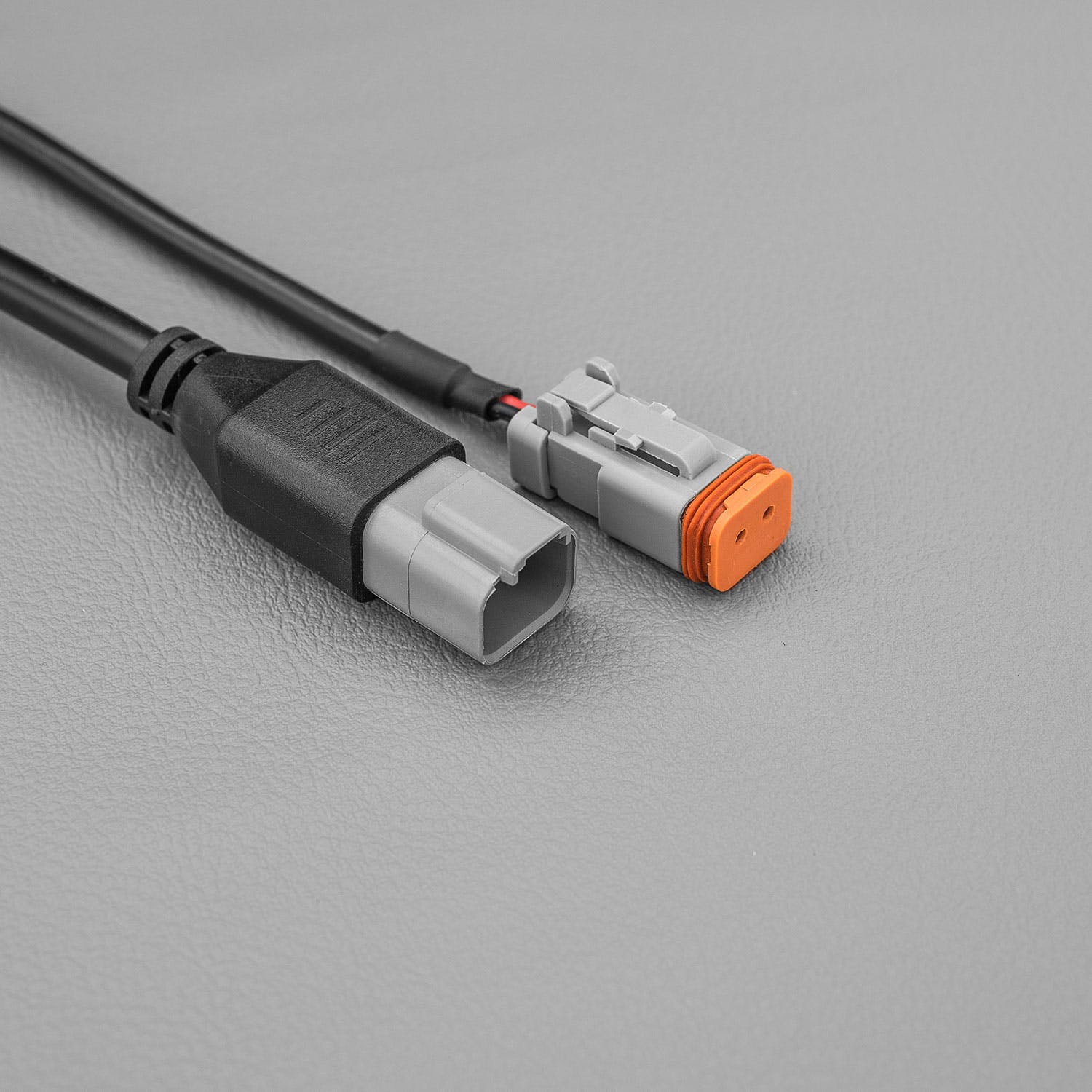 Cable ending in a grey plug beside a matching plug with an orange lock