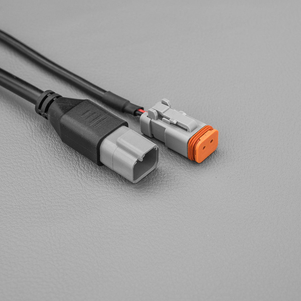 Cable ending in a grey plug beside a matching plug with an orange lock