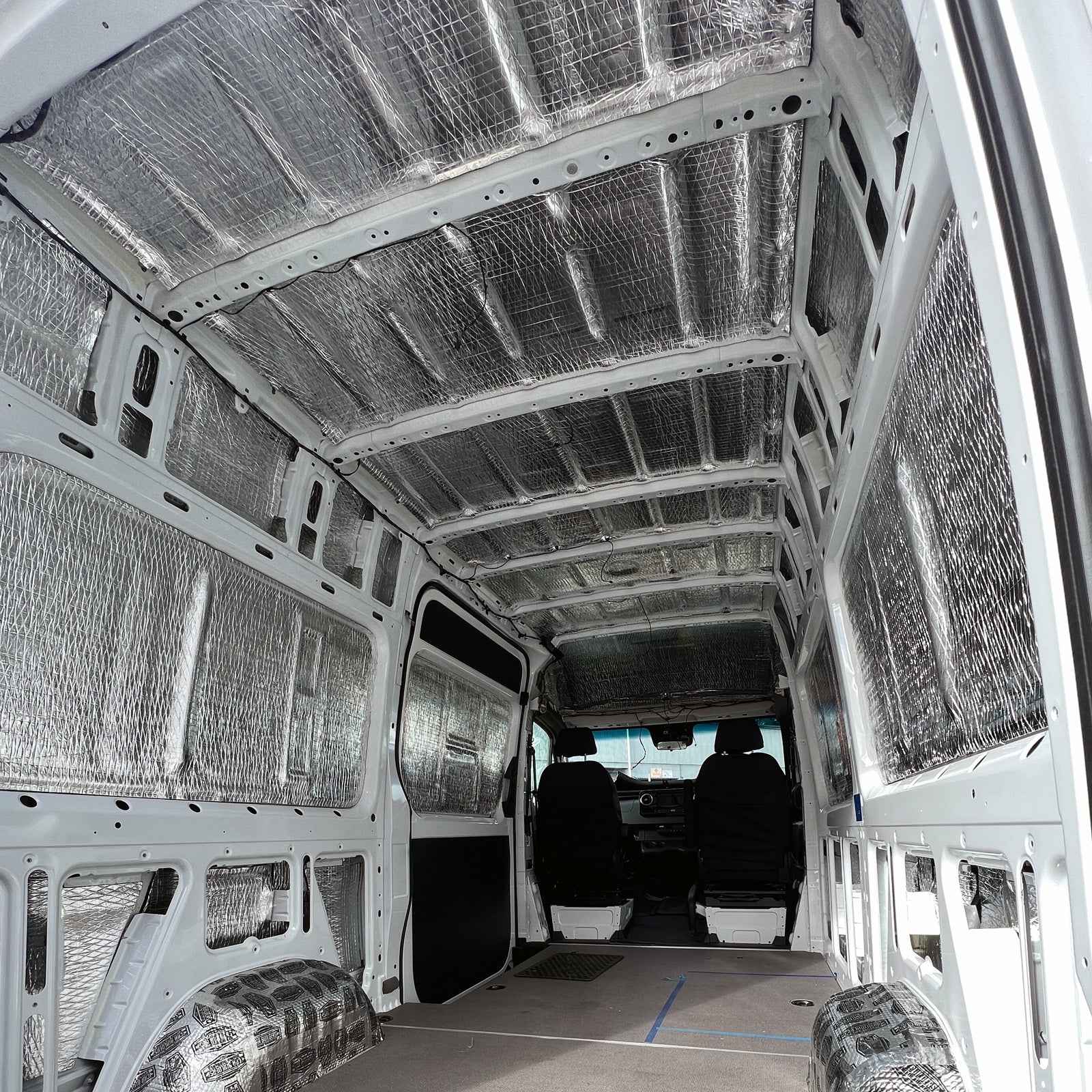 Sprinter medium wheelbase cargo area lined with precut Van Liner, looking forward